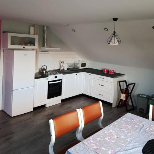 a kitchen with white cabinets and an orange chair in it at LawendoweAgro in Bytów