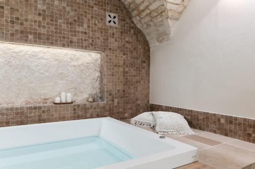 a bath tub in a bathroom with a brick wall at Alba Luxury Suite in Ostuni