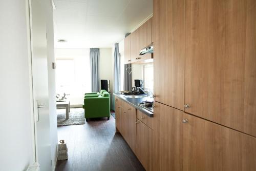 a kitchen with wooden cabinets and a green chair at EuroParcs Schoneveld in Breskens