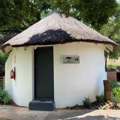 a small hut with a thatched roof and a door at Pretoria Country Club - Old Tree Hut in Pretoria