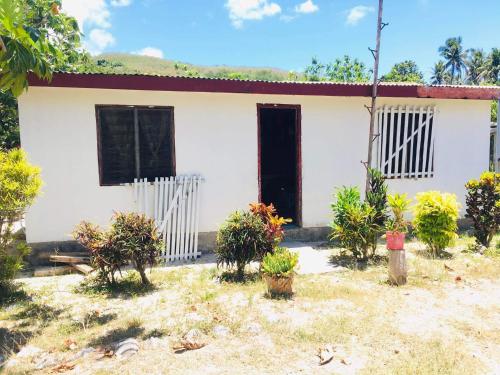 a white house with a black door and some plants at Yasawa Homestays in Nacula Island