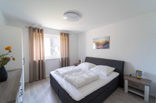 ein Schlafzimmer mit einem Bett mit weißen Laken in der Unterkunft Seevilla am See mit Sauna, Kamin, privatem Steg und Seezugang in Barßel