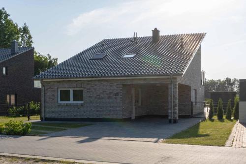 ein Backsteinhaus mit einem Dach auf einer Auffahrt in der Unterkunft Seevilla am See mit Sauna, Kamin, privatem Steg und Seezugang in Barßel