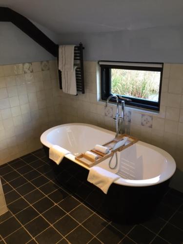 a bath tub in a bathroom with a window at De Beijersche Stee , Landhuysje in Stolwijk