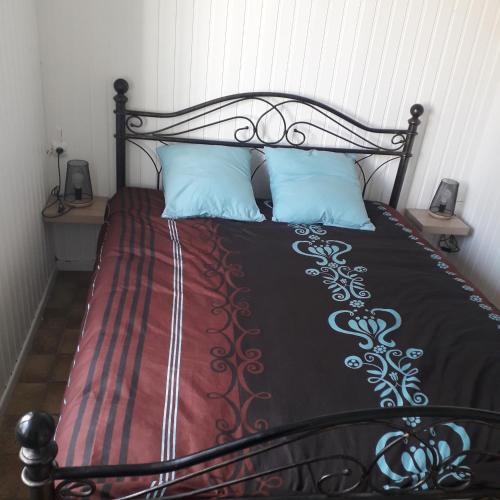 a bed with a black and red comforter and blue pillows at petite maison plain pied proche dunkerque in Boomkens