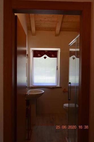 bagno con lavandino e finestra di Alloggio agrituristico Pociat 