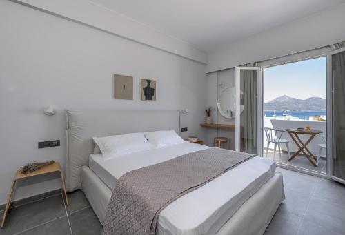 a white bedroom with a large bed and a balcony at Hotel Ippocampos Studios in Adamas