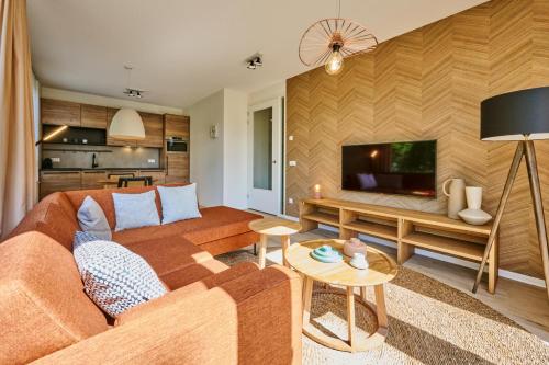 a living room with a couch and a flat screen tv at Dormio Resort Maastricht Castellum Apartments in Maastricht