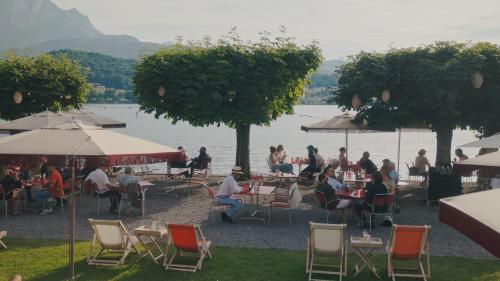 a picnic table with chairs and umbrellas on a sunny day at HERMITAGE Lake Lucerne in Lucerne