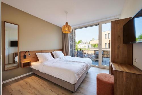 a bedroom with a bed and a large window at Dormio Resort Maastricht Castellum Apartments in Maastricht