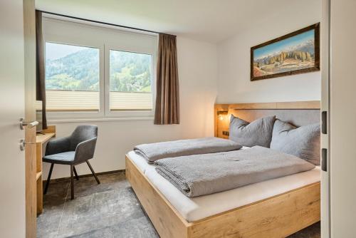 a bedroom with a bed and a chair and a window at Neues luxeriös eingerichtetes Apartment Bock in See