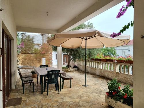 een patio met een tafel en stoelen en een parasol bij Vacation house Delić in Dugi Rat