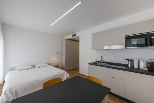 a white bedroom with a bed and a black table at Modern Studios Mendrisio in Mendrisio