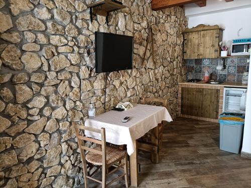a kitchen with a table and a tv on a stone wall at Casolare La Torre in Scopello
