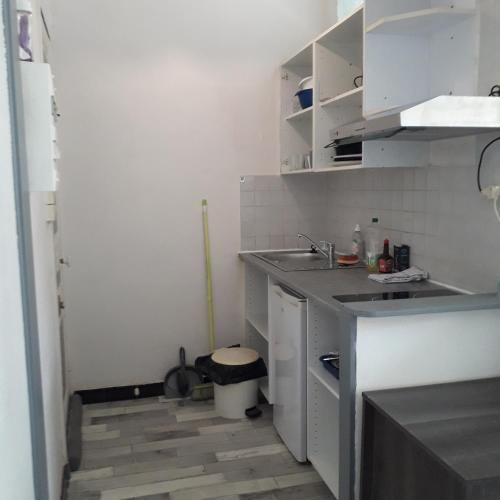 una pequeña cocina con armarios blancos y fregadero en studio malo les bains dunkerque, en Dunkerque