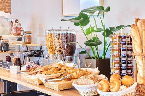 a table with baskets of bread and pastries on it at Kyriad Lille Est - Villeneuve d'Ascq in Villeneuve d'Ascq