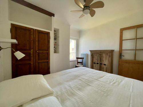 une chambre avec un lit blanc et un ventilateur de plafond dans l'établissement La Maison de Lily, cosy dans le Vieux-Hyères, parking gratuit, à Hyères