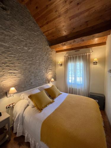 a bedroom with a large bed with a stone wall at MESON DU BONHEUR in Osséja