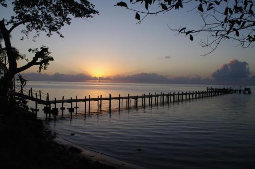 a dock on a lake with the sun setting in the background at Boraha Village Ecolodge in Sainte Marie