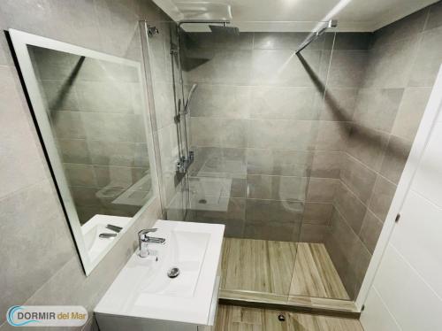 a bathroom with a sink and a shower with a mirror at Dormir del Mar in La Marina