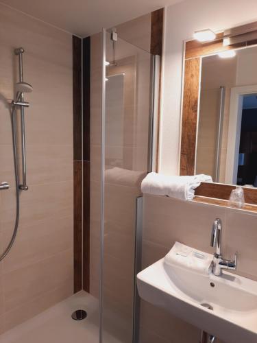 La salle de bains est pourvue d'une douche, d'un lavabo et d'un miroir. dans l'établissement Gasthaus Kempermann, à Großenkneten