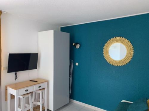 Cette chambre est dotée d'un mur bleu avec un miroir et d'un bureau. dans l'établissement Studio Cap d'Agde avec piscine proche de la mer, au Cap d'Agde