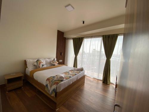 a bedroom with a bed and a large window at Janeira in Shillong