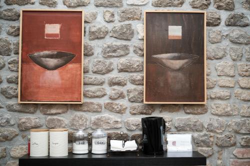 two paintings on a wall with a table with cups at Agriturismo Castello Santa Margherita in Cori