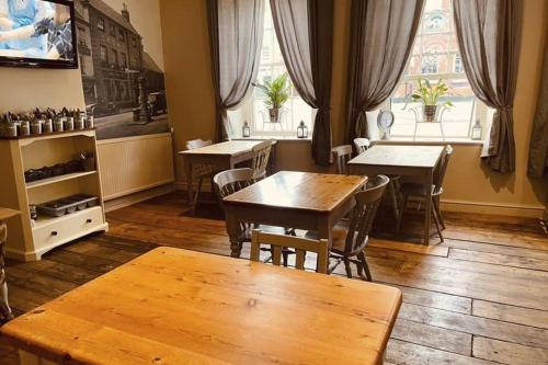 a dining room with tables and chairs and windows at The Crown Fakenham in Fakenham