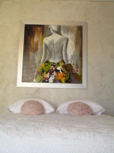 une peinture d'une femme sur un lit avec deux oreillers dans l'établissement Le Mas du Fort, à Neyron