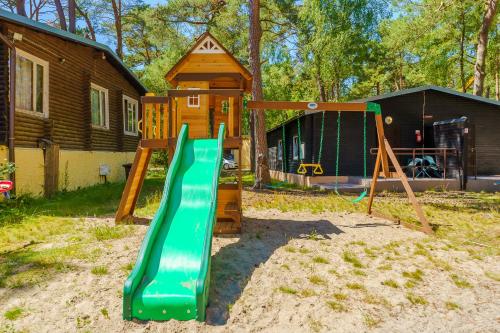 a playground with a green slide in front of a house at Terimex in Pogorzelica