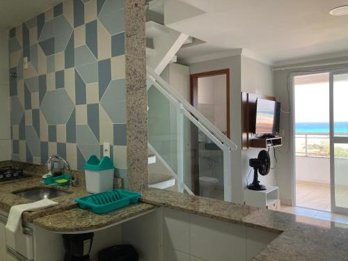 a bathroom with a sink and a mirror and a television at Duplex da Praia Grande in Arraial do Cabo