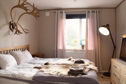 1 dormitorio con 1 cama con manta de piel y ventana en Långforsen Glamping & Lapland Experience, 