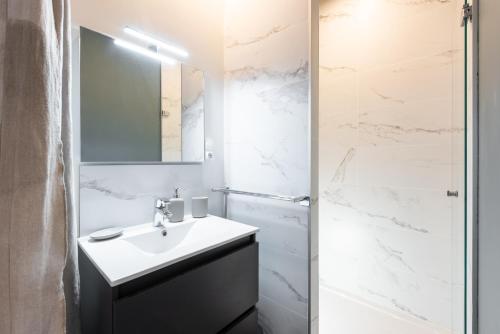 ein weißes Bad mit einem Waschbecken und einer Dusche in der Unterkunft LE SHERWOOD - Magnifique T3 avec bureau in Villeurbanne