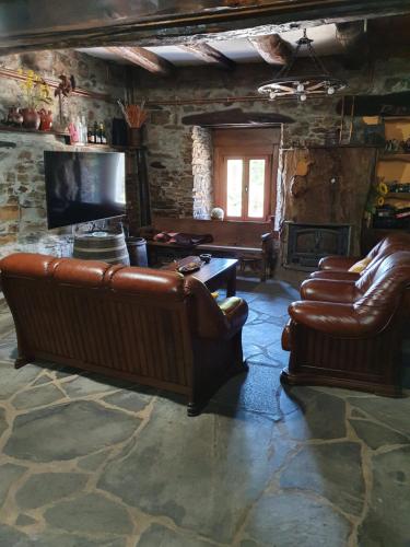 sala de estar con sofás de cuero y TV de pantalla plana en Casa Regueirín, en Lugo