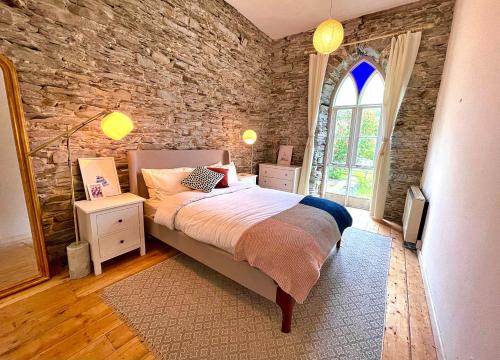 a bedroom with a bed and a stone wall at Finest Retreats - Luxury Converted Chapel with Hot Tub & Games Room in Dinas Mawddwy