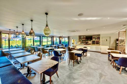 a restaurant with tables and chairs and windows at Kyriad Hotel Meaux in Meaux