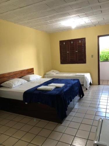 a bedroom with two beds with blue sheets and a window at Pousada Vale do Gravatá in Gravatá