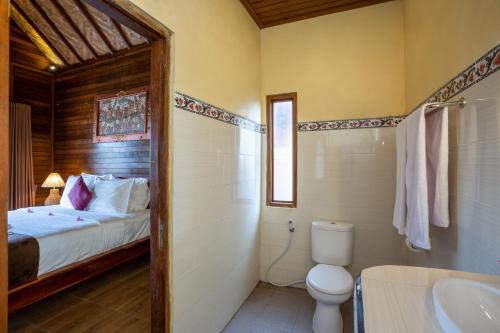 y baño con cama, aseo y lavamanos. en Rijet Villa Beach & Restaurant en Nusa Penida