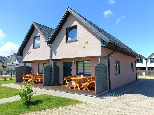 ein Haus mit einer Terrasse mit Holztischen in der Unterkunft Słoneczny Raj Apartamenty Domki apartamentowe in Sarbinowo