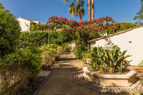 een tuin met bloeiende planten en een gebouw bij Hôtel La Tartane Saint-Tropez in Saint-Tropez