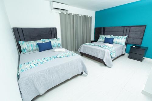 two beds in a room with blue walls at Skylight Suites Hotel in San Felipe de Puerto Plata