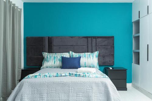 a blue bedroom with a bed with a blue wall at Skylight Suites Hotel in San Felipe de Puerto Plata