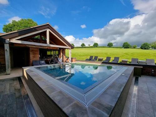 a swimming pool with chairs and a house at Moddershall Oaks Country Spa Retreat in Stone