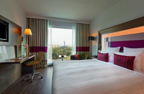 a hotel room with a large bed and a window at Novotel Chennai Sipcot in Chennai