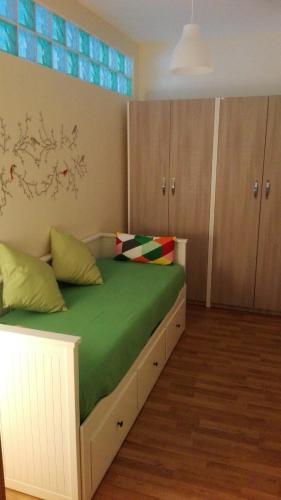a bedroom with a bed with green sheets and wooden cabinets at Scario Sunny Apartment in centro in Scario