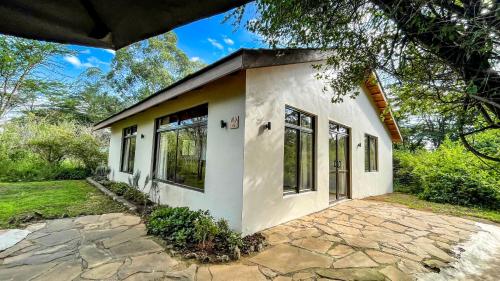 a small white house with a stone patio at The Senna House in Nakuru
