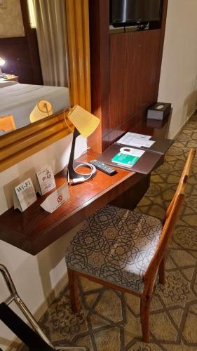 a desk with a lamp and a chair next to a bed at Jiwar Al Madina Hotel in Al Madinah