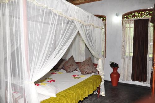1 dormitorio con cama con dosel y cortinas blancas en Homestay Orchid, en Mahawatta