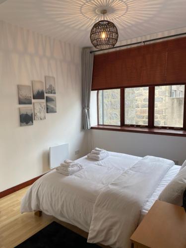 a bedroom with a white bed and a window at Charlotte Street Apartment in Aberdeen